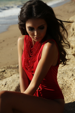 fashion outdoor photo of gorgeous sexy woman with dark hair in elegant swimsuit posing on summer beachの写真素材