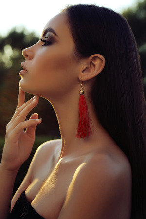 fashion  photo of gorgeous woman with long dark hair and bright makeup posing outdoorの写真素材