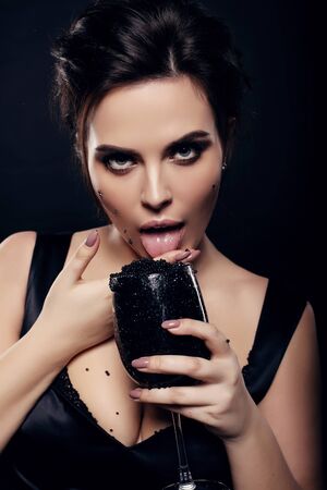 fashion studio photo of sexy gorgeous woman with dark hair eating black caviarの写真素材