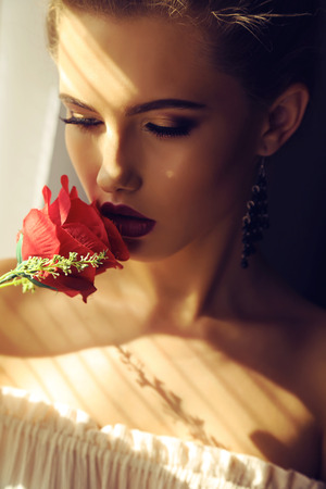 fashion studio portrait of beautiful young woman with dark natural hair posing in shadowの写真素材