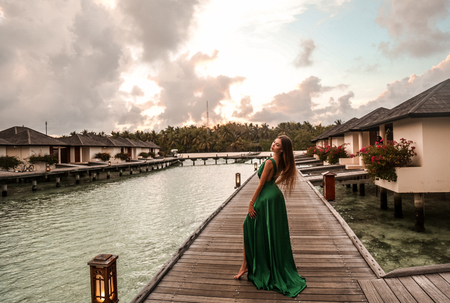 fashion photo of beautiful sexy girl with dark hair in elegant beach clothes, relaxing on Maldive island beachの写真素材