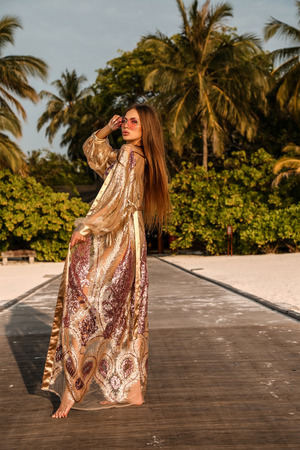 fashion photo of beautiful sexy girl with dark hair in elegant beach clothes, relaxing on Maldive island beachの写真素材