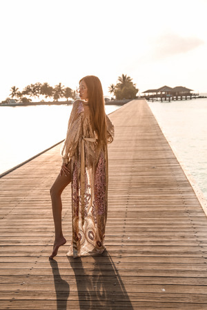 fashion photo of beautiful sexy girl with dark hair in elegant beach clothes, relaxing on Maldive island beachの写真素材