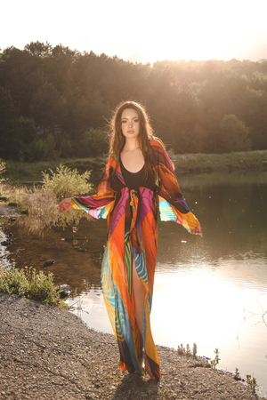 fashion outdoor photo of beautiful sexy woman with brunette hair in elegant swimming suit posing in nice nature place, a lake surrounded by mountainsの写真素材