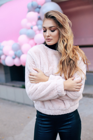 fashion outdoor photo of beautiful woman with blond hair in luxurious fur coat walking on the streetの写真素材