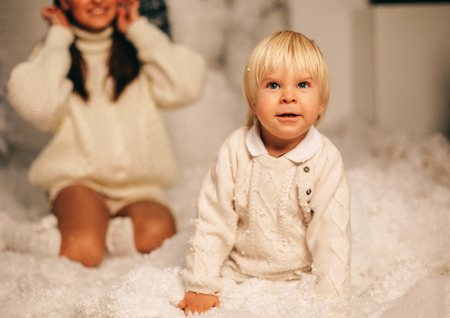 holiday Christmas photo of small cute boy and his beautiful mother playing with toys in decorated homeの写真素材