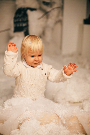 holiday Christmas photo of small cute boy playing with toys in decorated homeの写真素材