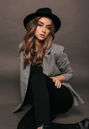 fashion studio photo of beautiful sexy woman with blond hair in elegant chic jacket  and black hatの写真素材