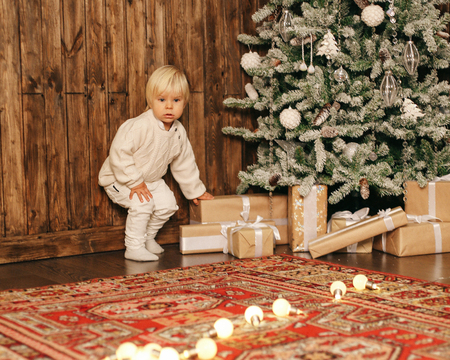 holiday Christmas photo of small cute boy playing with toys in decorated homeの写真素材