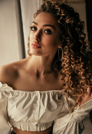 fashion photo of beautiful sexy woman with long blond curly hair in elegant clothes posing in studioの写真素材