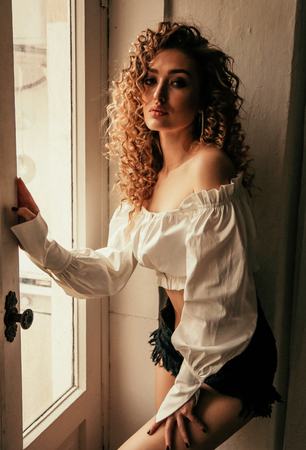 fashion photo of beautiful sexy woman with long blond curly hair in elegant clothes posing in studioの写真素材