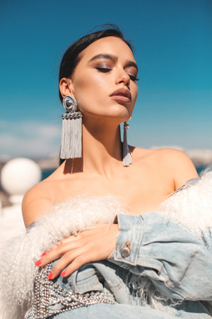 fashion outdoor photo of beautiful sexy woman with dark hair in luxurious clothes walking by the spring cityの写真素材