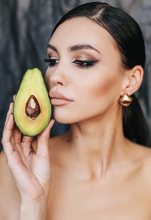 fashion studio photo of beautiful woman with dark hair posing with avocadoの写真素材