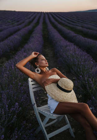 fashion outdoor photo of beautiful sexy woman with blond hair in elegant clothes with accessories posing in blooming lavender fieldsの写真素材
