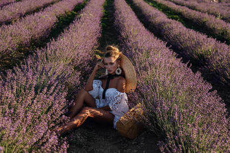 fashion outdoor photo of beautiful sexy woman with blond hair in elegant clothes with accessories posing in blooming lavender fieldsの写真素材