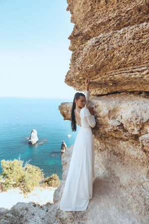 fashion outdoor photo of beautiful woman with dark hair in luxurious wedding dress and accessories posing in beautiful landscapeの写真素材