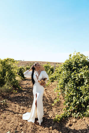 fashion outdoor photo of beautiful woman with dark hair in luxurious wedding dress and accessories posing in beautiful landscapeの写真素材