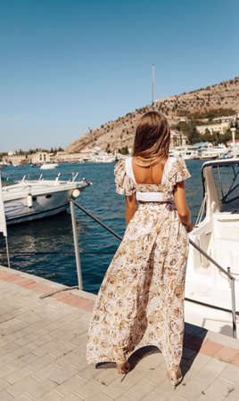 fashion outdoor photo of beautiful sexy woman with blond hair in elegant dress posing on yacht with sea viewの写真素材
