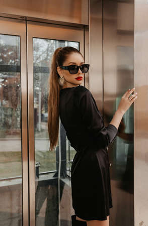fashion outdoor photo of beautiful sexy woman with blond hair in elegant clothes and sunglasses posing near metal elevatorの写真素材
