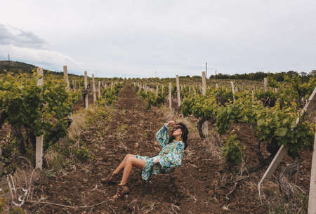 fashion outdoor photo of beautiful woman with dark hair in elegant dress posing in vineyardの写真素材