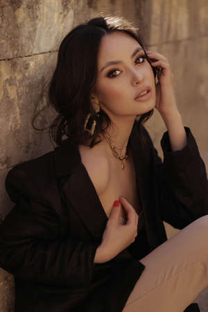 fashion outdoor photo of beautiful woman with dark hair in elegant dress posing on the streetの写真素材