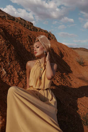 fashion outdoor photo of beautiful woman with blond hair in elegant dress posing in desert