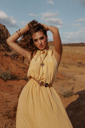 fashion outdoor photo of beautiful woman with blond hair in elegant dress posing in desert