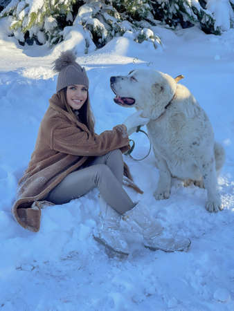 fashion outdoor photo of beautiful woman with dark hair in elegant clothes posing in the snowy...