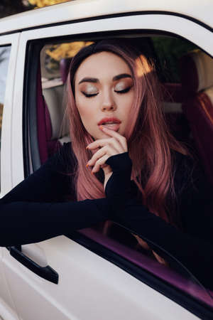 fashion photo of beautiful woman with dark hair in elegant clothes posing in the retro carの写真素材