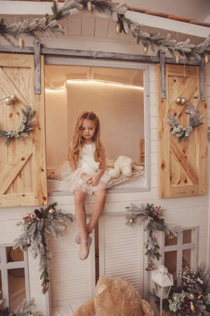 fashion photo of beautiful cute little girl posing in decorated studio with Christmas treeの写真素材