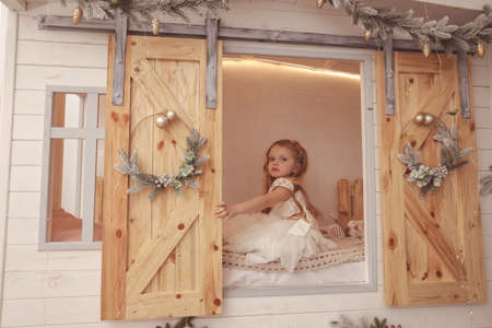 fashion photo of beautiful cute little girl posing in decorated studio with Christmas treeの写真素材