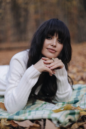 fashion outdoor photo of beautiful woman with dark hair in elegant clothes and accessories posing in autumn forestの写真素材
