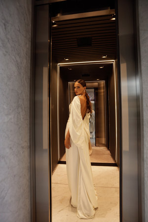 fashion photo of beautiful bride in elegant wedding dress and accessories posing in elegant hotel roomの写真素材