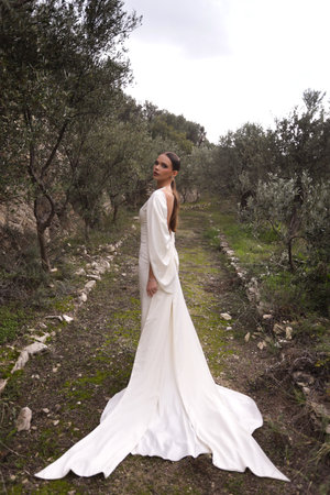 fashion outdoor photo of beautiful woman with dark hair in luxurious wedding dress with jewelry posing in beautiful nature place Lefkara, with mountains in the backgroundの写真素材