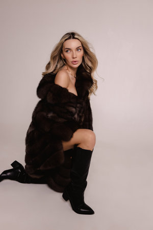 fashion photo of beautiful sexy woman with blond hair in luxurious fur coat posing in the studioの写真素材