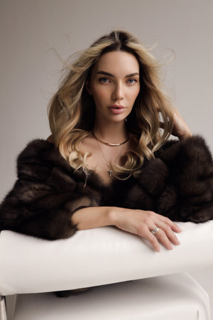 fashion photo of beautiful sexy woman with blond hair in luxurious fur coat posing in the studioの写真素材