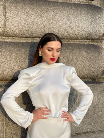 fashion outdoor photo of beautiful woman with dark hair in luxurious white silk dress and accessories posing by the Alexandre III bridge in Parisの写真素材