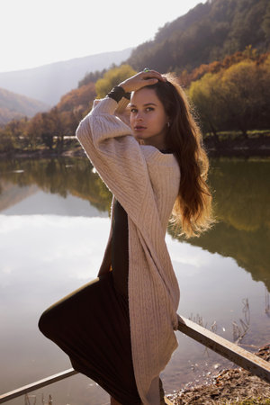fashion outdoor photo of beautiful woman with dark hair in elegant dress and wool coat posing among beautiful natureの写真素材