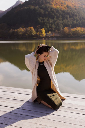 fashion outdoor photo of slavic woman with dark hair in elegant dress and wool coat posing among beautiful natureの写真素材