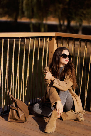 fashion outdoor photo of slavic woman with dark hair in elegant dress and wool coat posing among beautiful natureの写真素材