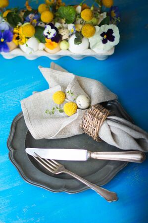 Easter holiday table setting with first spring flowers like tricolor violas and primerose , colored eggsの写真素材