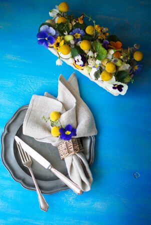 Easter holiday table setting with first spring flowers like tricolor violas and primerose , colored eggsの写真素材