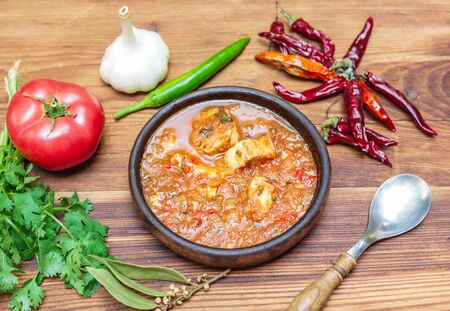 Chakhokhbili - Georgian traditional dish of stewed chicken, tomato with herbsin in a clay bowl on a wooden tableの写真素材