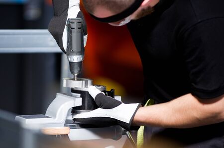 working man in a black t-shirt at a workbench working with a screwdriverの写真素材