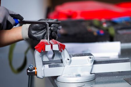 in the photo, a hand in a gray working glove is finalizing a metal workpiece clamped in a viceの写真素材