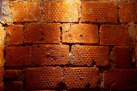 a large fragment of a red brick rough wall with a lantern shining on topの写真素材
