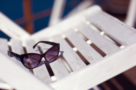 sunglasses lie on a wooden white sunbed with peeling paintの写真素材