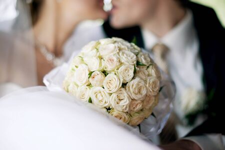 round bouquet of white roses on a background of kissing newlyweds, close-upの写真素材