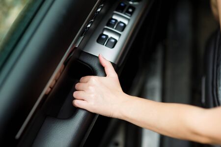 girl holds the inner door handle of a car, about to close itの写真素材