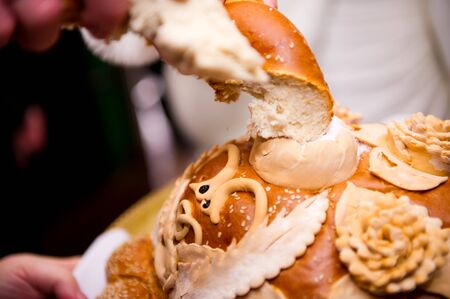 a piece of wedding loaf is dipped in salt. image of bread and salt at a wedding